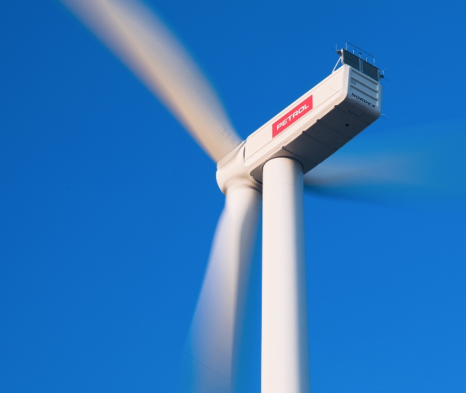 Vjetroturbina s Petrolovim logotipom proizvodi energiju pod vedrim plavim nebom.